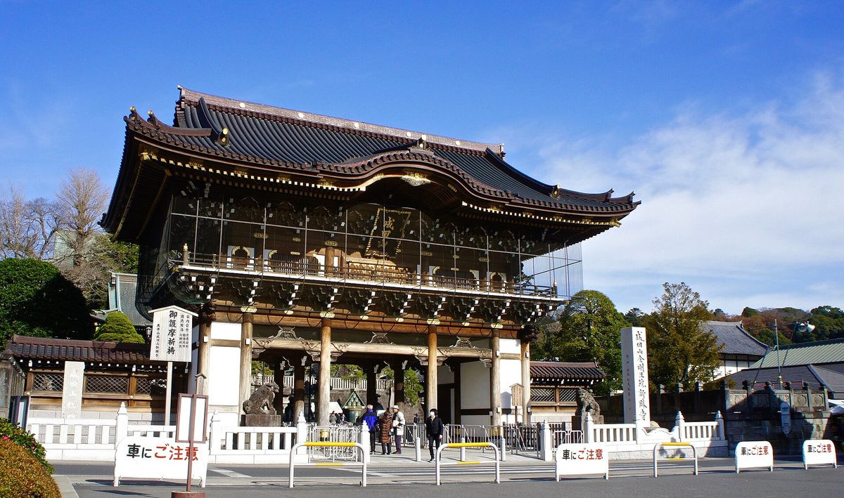 A large wooden temple gate at Naritasan Shinshoji under a blue sky