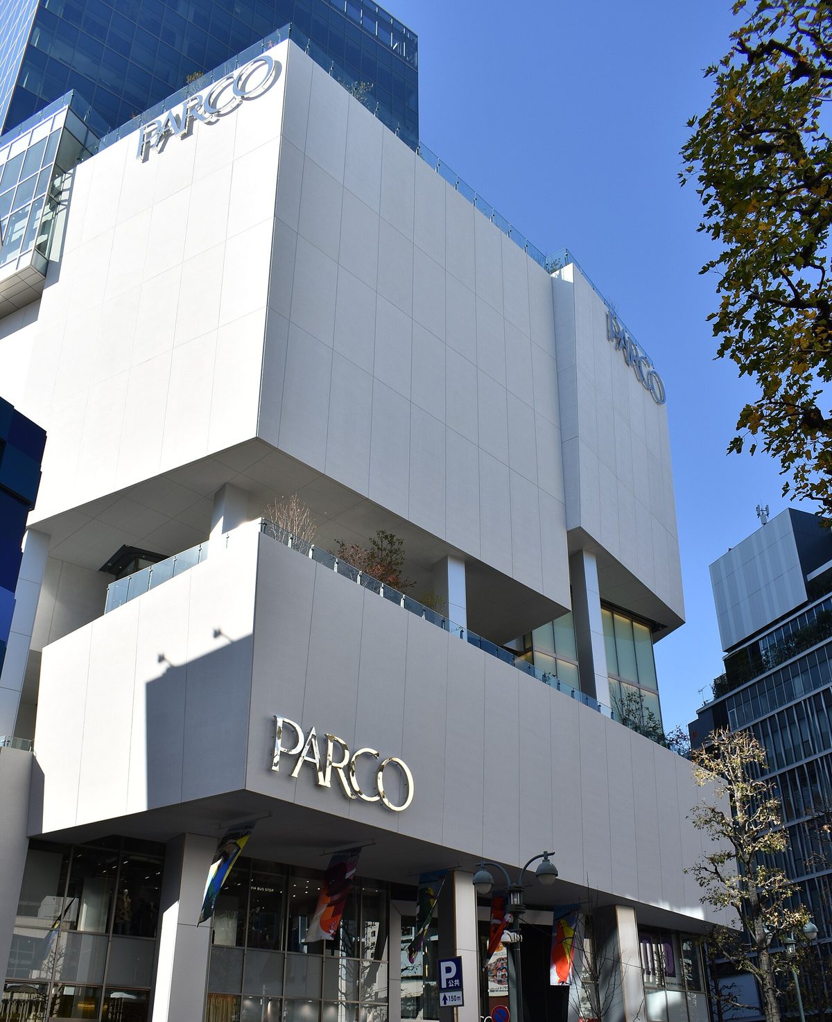 The white, boxy facade of the PARCO building in Shibuya, Tokyo (Tokyo), with the PARCO sign under a blue sky