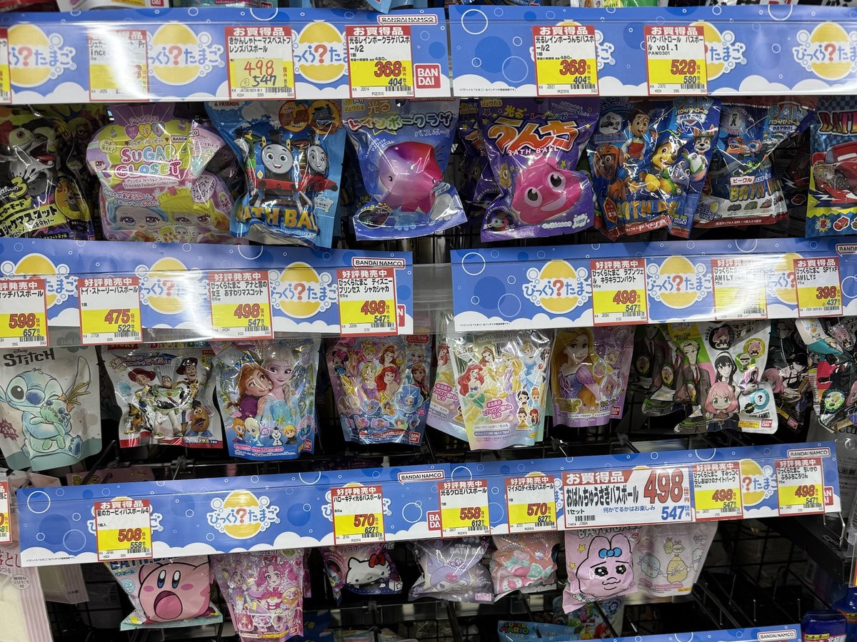 Rows of Bikkura Tamago bath bomb packs with character designs hanging under blue price rails
