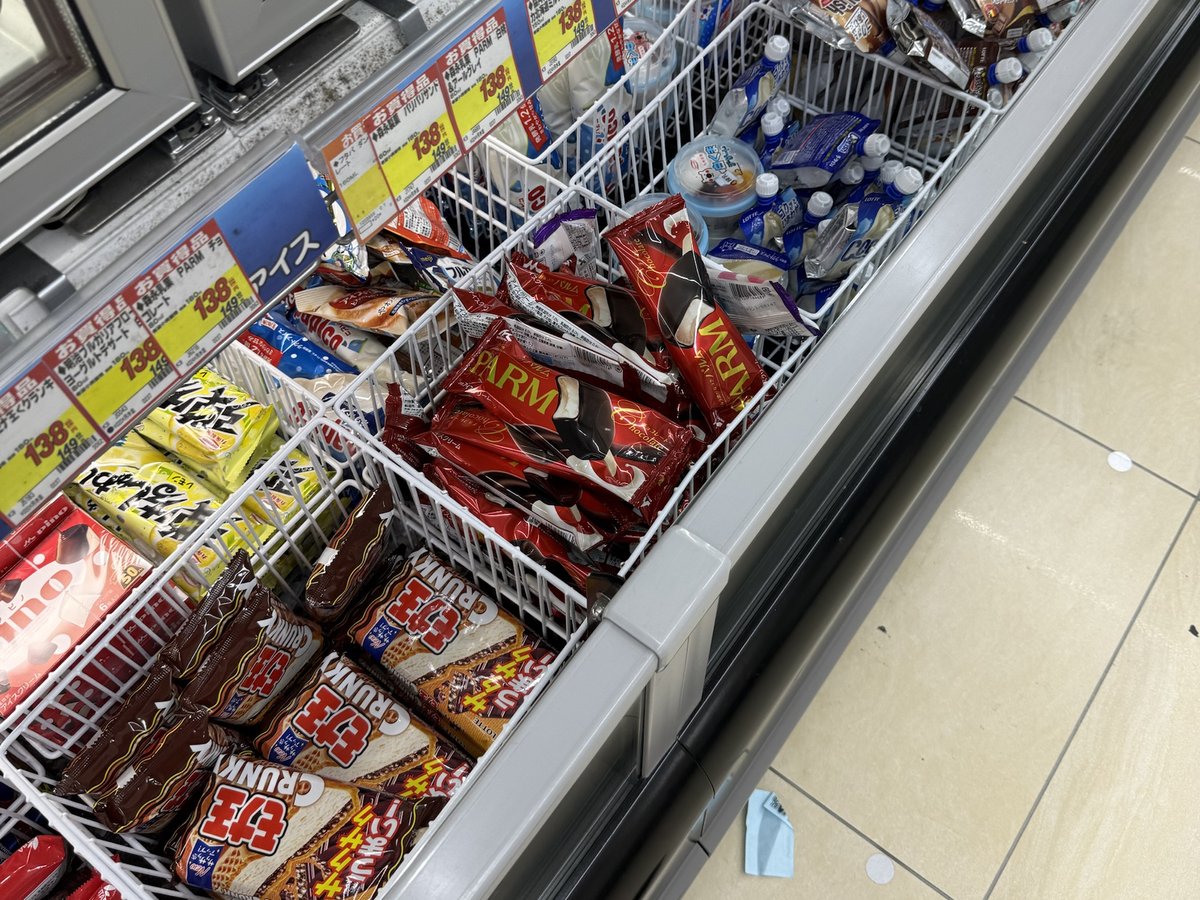 An open freezer at a drugstore with baskets of wrapped ice cream bars and price tags along the edge