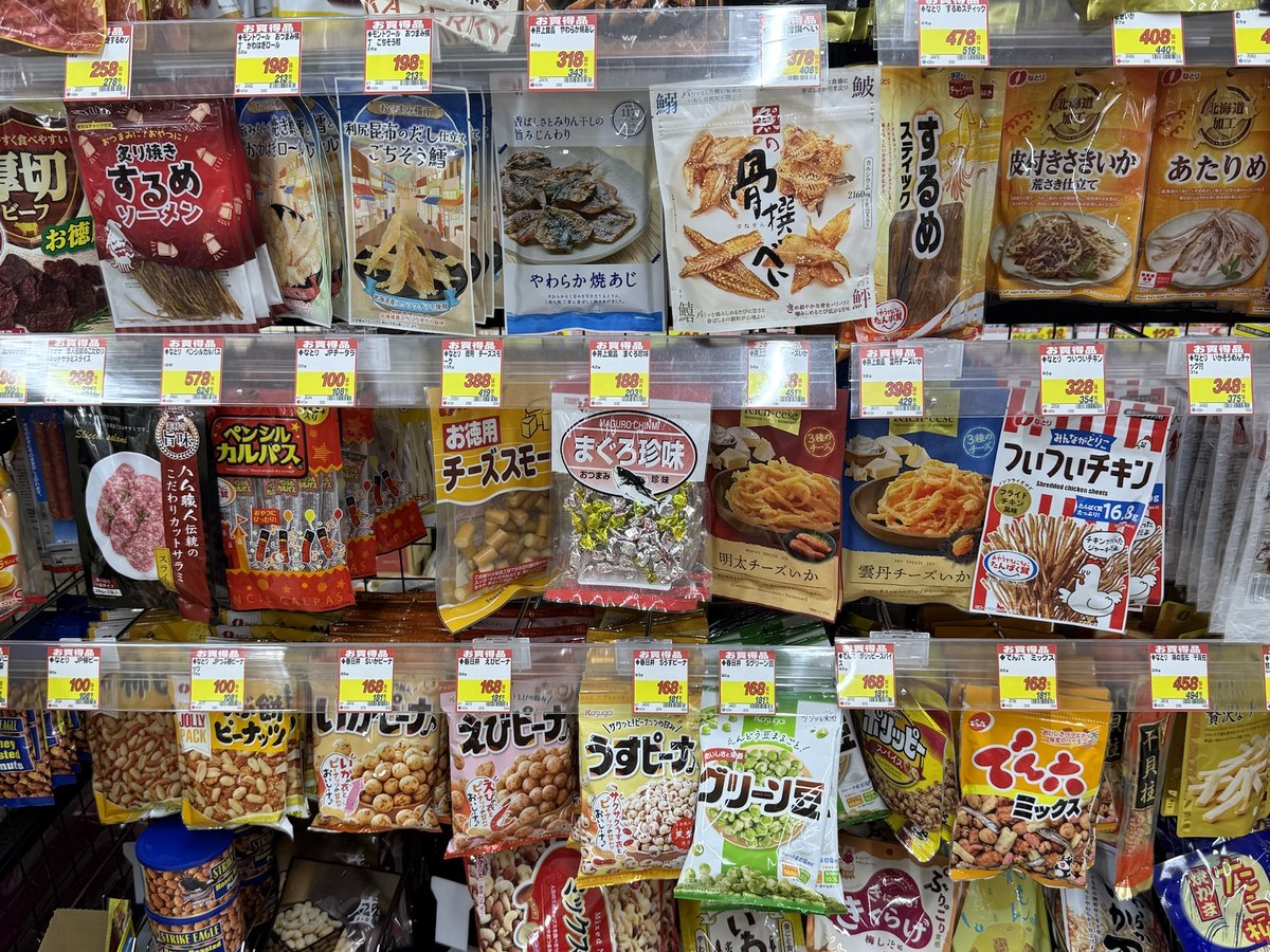 Bags of dried squid, jerky, cheese snacks and flavored peanuts hanging on a drugstore rack with price tags