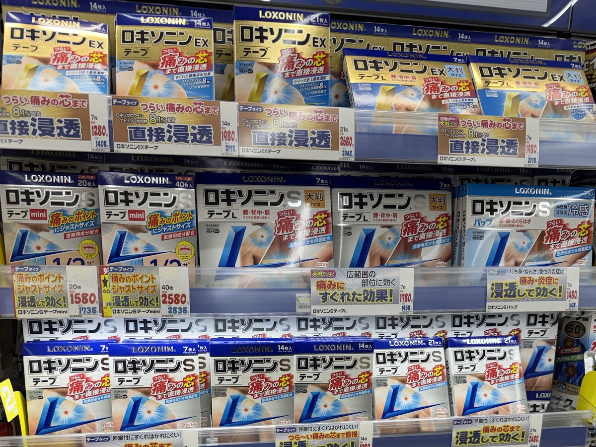 Rows of Loxonin S and Loxonin EX tape boxes on drugstore shelves with price cards