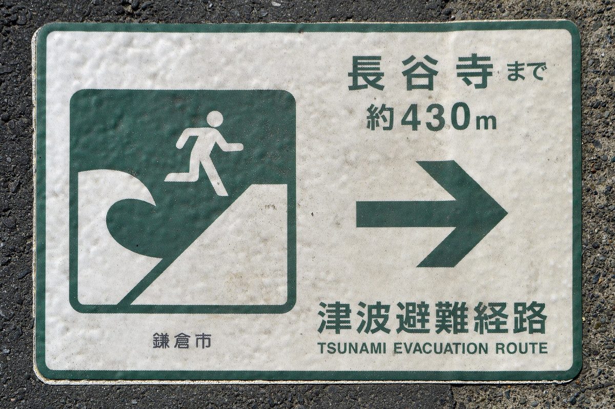 A green tsunami evacuation route sign painted on the road