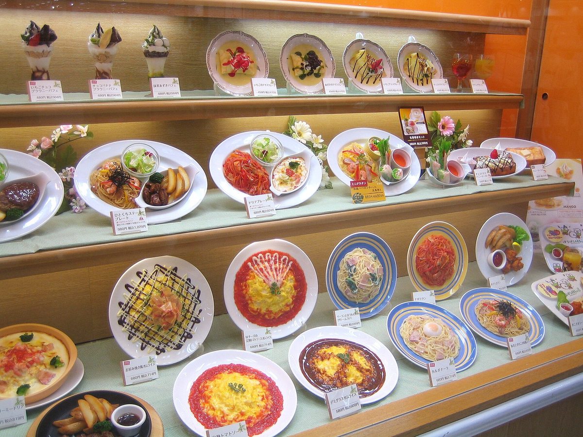 A restaurant window display of plastic food samples with price labels