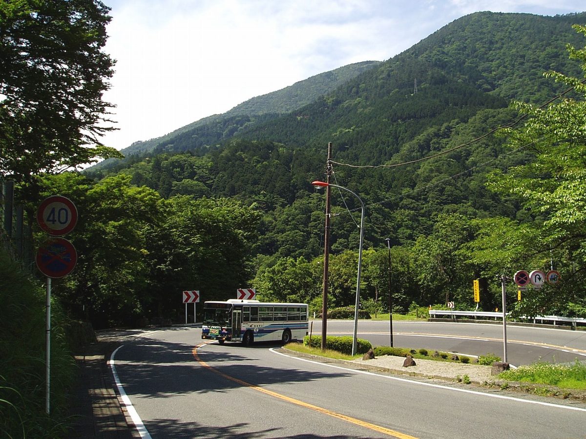 A local bus (Hakone Tozan Bus) on a mountain road among green hills in Hakone (Kanagawa)