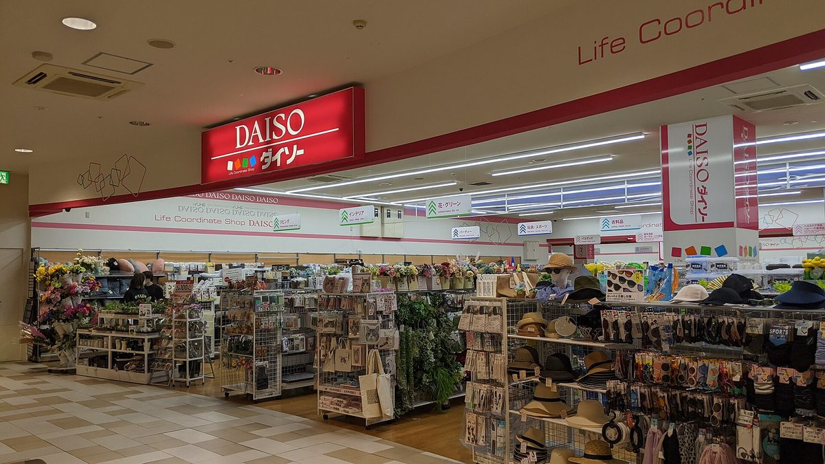 The entrance of a DAISO store inside a shopping mall, with shelves of household goods under a red DAISO sign