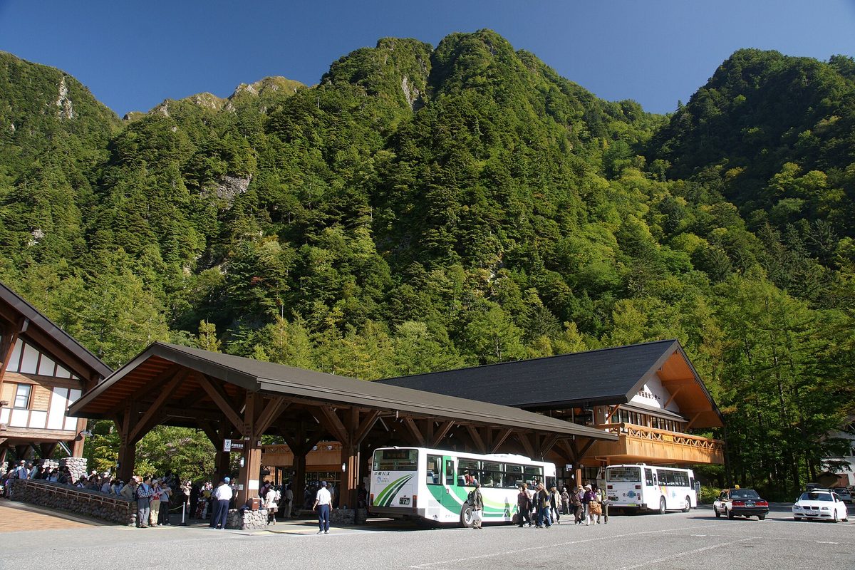 Buses at the bus terminal below green mountains in Kamikochi (Nagano)