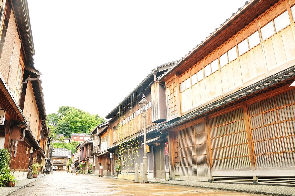 A stone-paved street in the Higashi Chaya District of Kanazawa (Ishikawa), lined on both sides with two-story wooden teahouse buildings with fine latticework