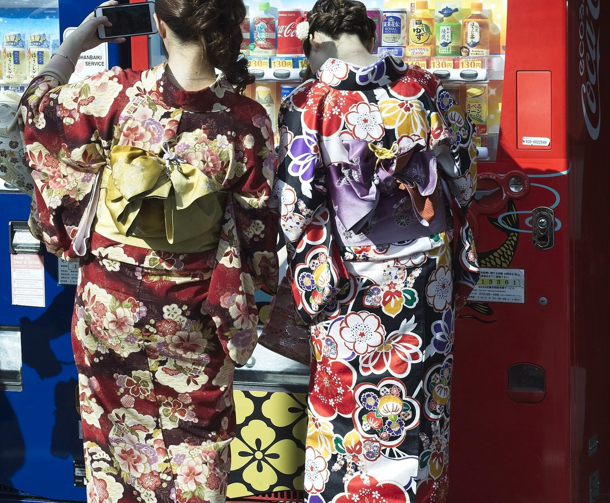 從背後看兩位穿著繽紛和服、繫著腰帶的人