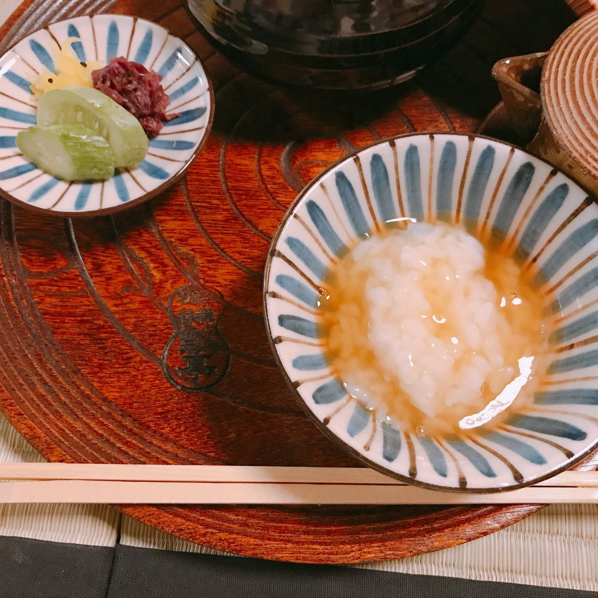 A close view of a striped bowl of soft white rice porridge with a glossy, light brown sauce poured over it