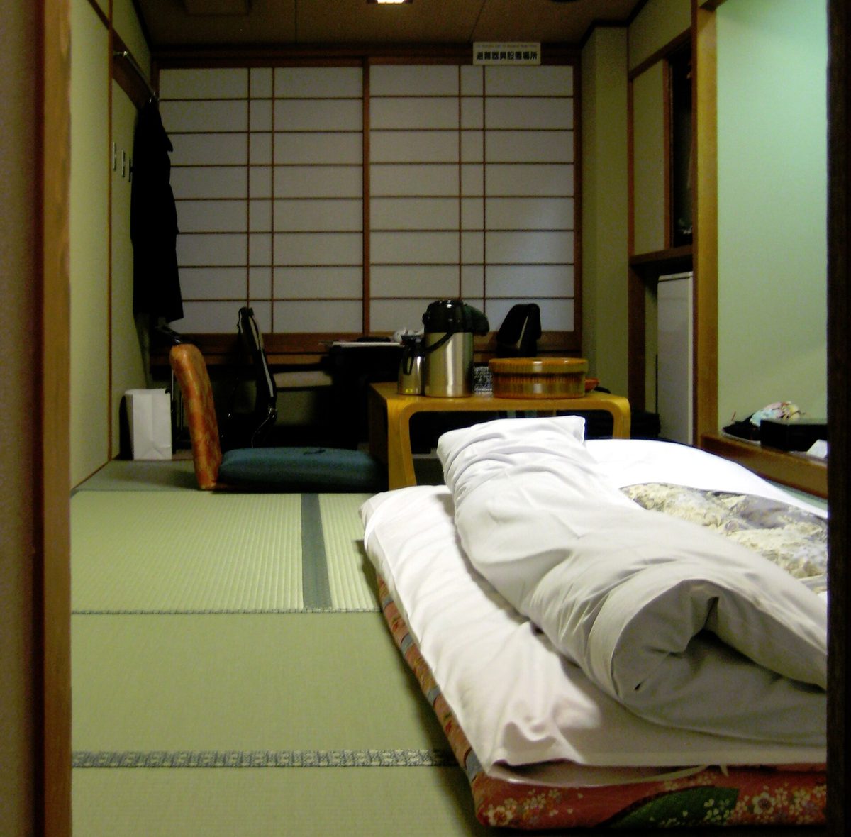 A tatami guest room at a ryokan with a futon laid out and shoji screens