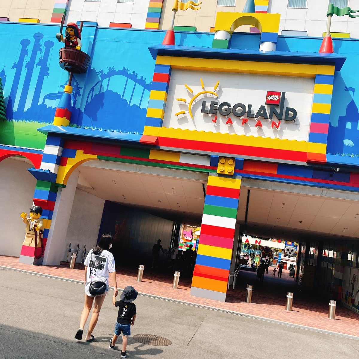 The colorful LEGOLAND Japan entrance gate, with an adult and a child seen from behind walking toward it