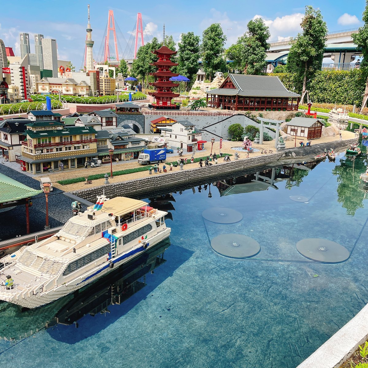 A LEGO model of a harbor with a white ship, a red pagoda and city buildings in Miniland