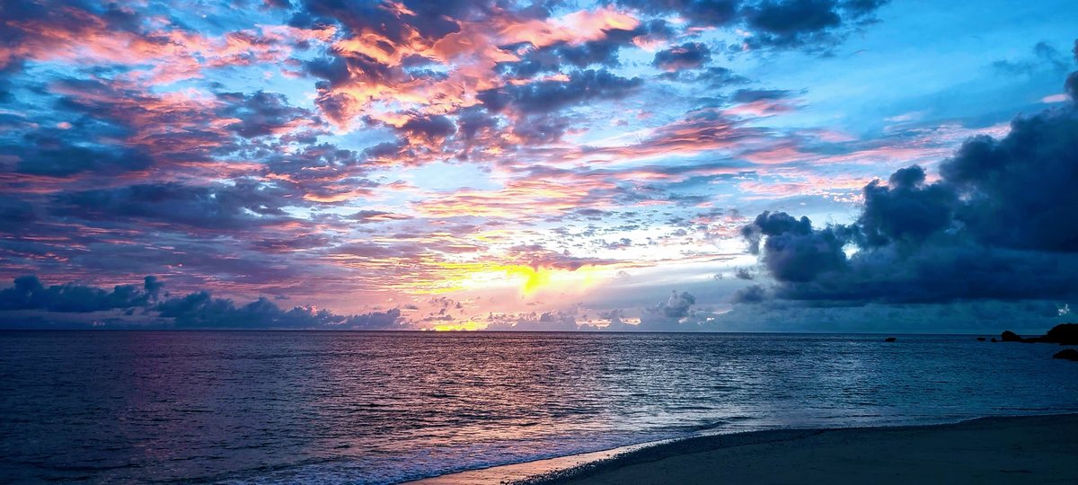 Pink and orange clouds over the sea at sunset, seen from a quiet beach