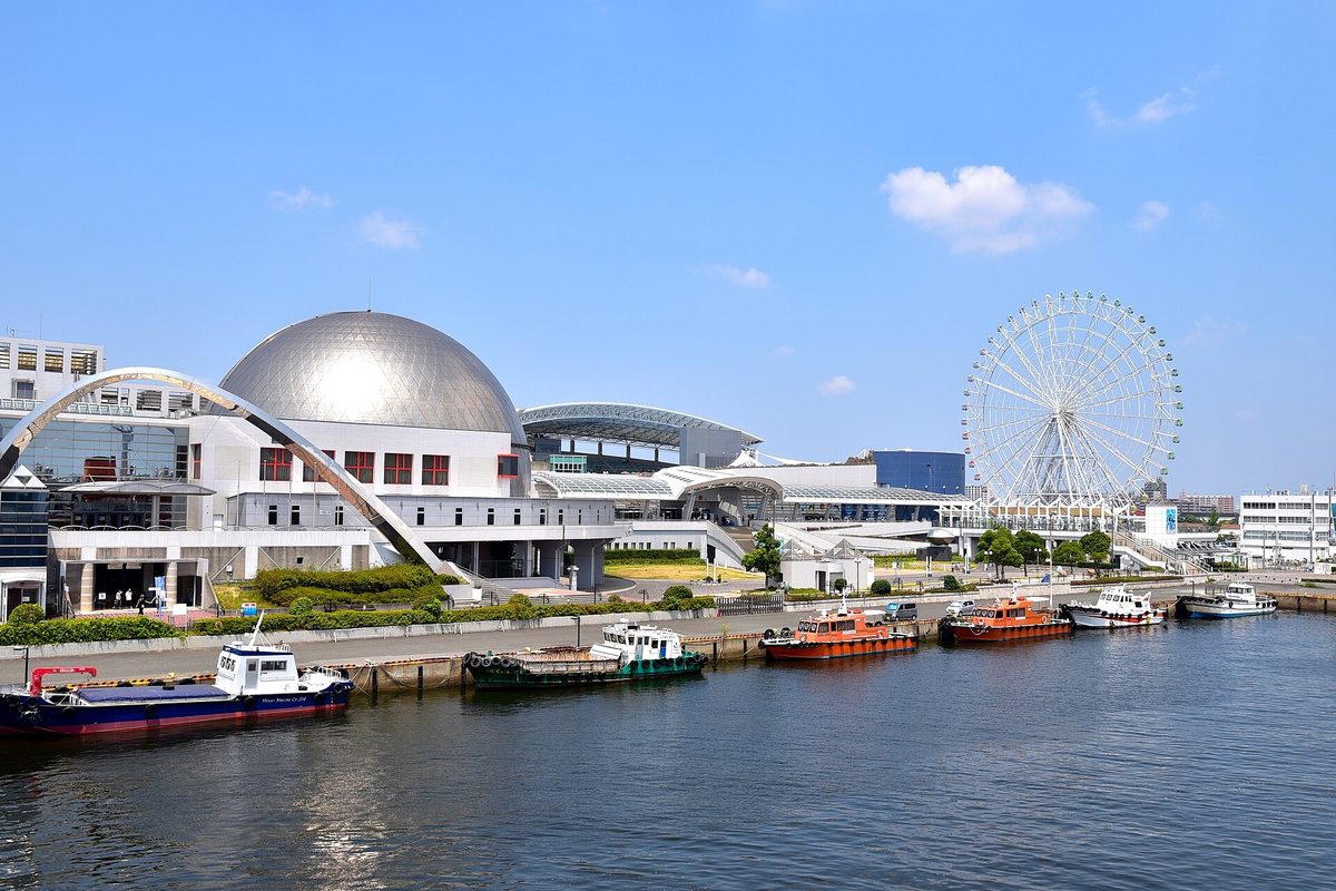 White buildings and a silver dome by the water at Garden Pier, with small boats in front and a Ferris wheel behind