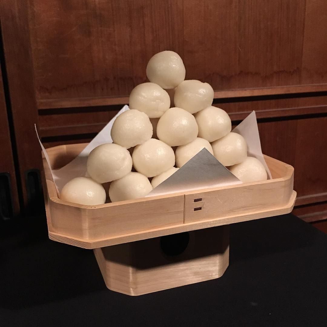 Round white tsukimi dango rice dumplings piled into a small pyramid on a wooden offering stand
