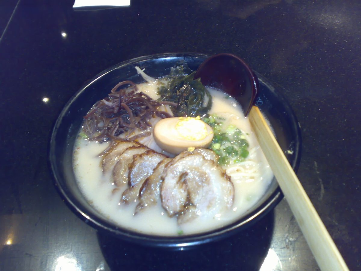 A bowl of creamy pork-bone ramen with sliced pork, egg and greens