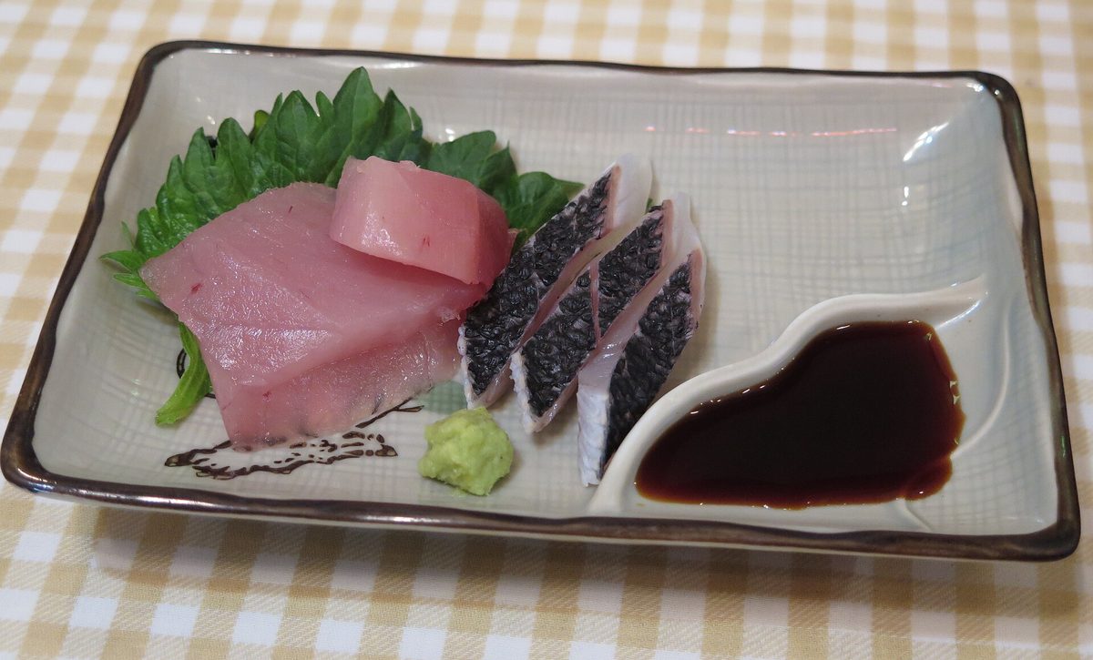 A plate of sashimi with wasabi and soy sauce