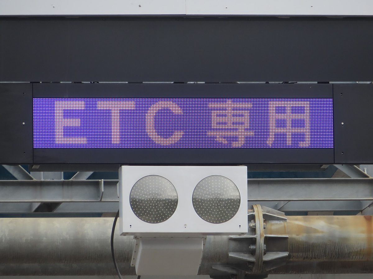 A purple electronic sign reading ETC only in Japanese above a toll lane, with a signal light below
