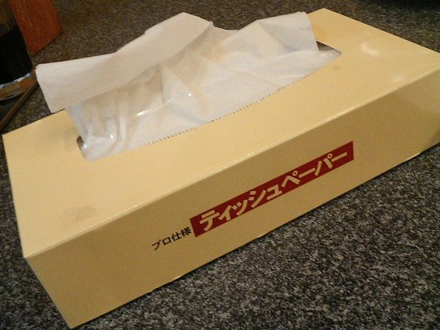 A box of tissues with a tissue pulled up from the opening