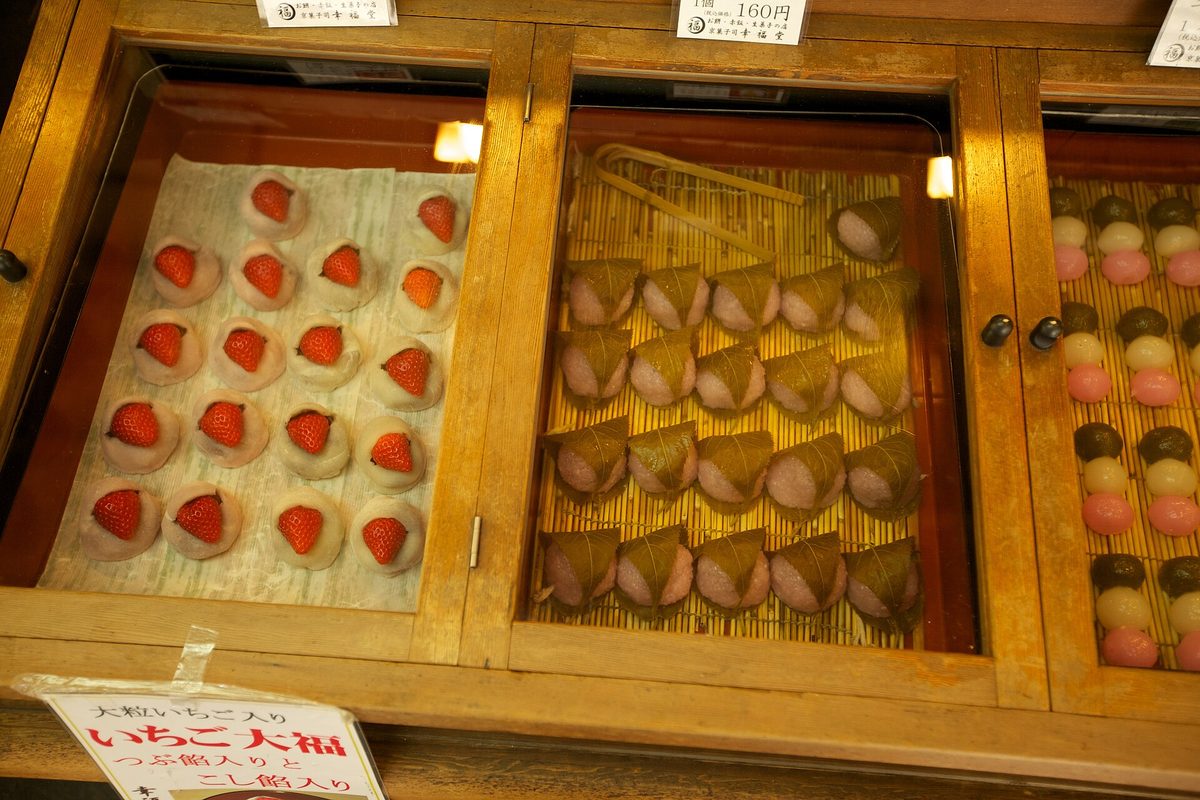 Trays of strawberry daifuku and other Japanese sweets in a shop display case