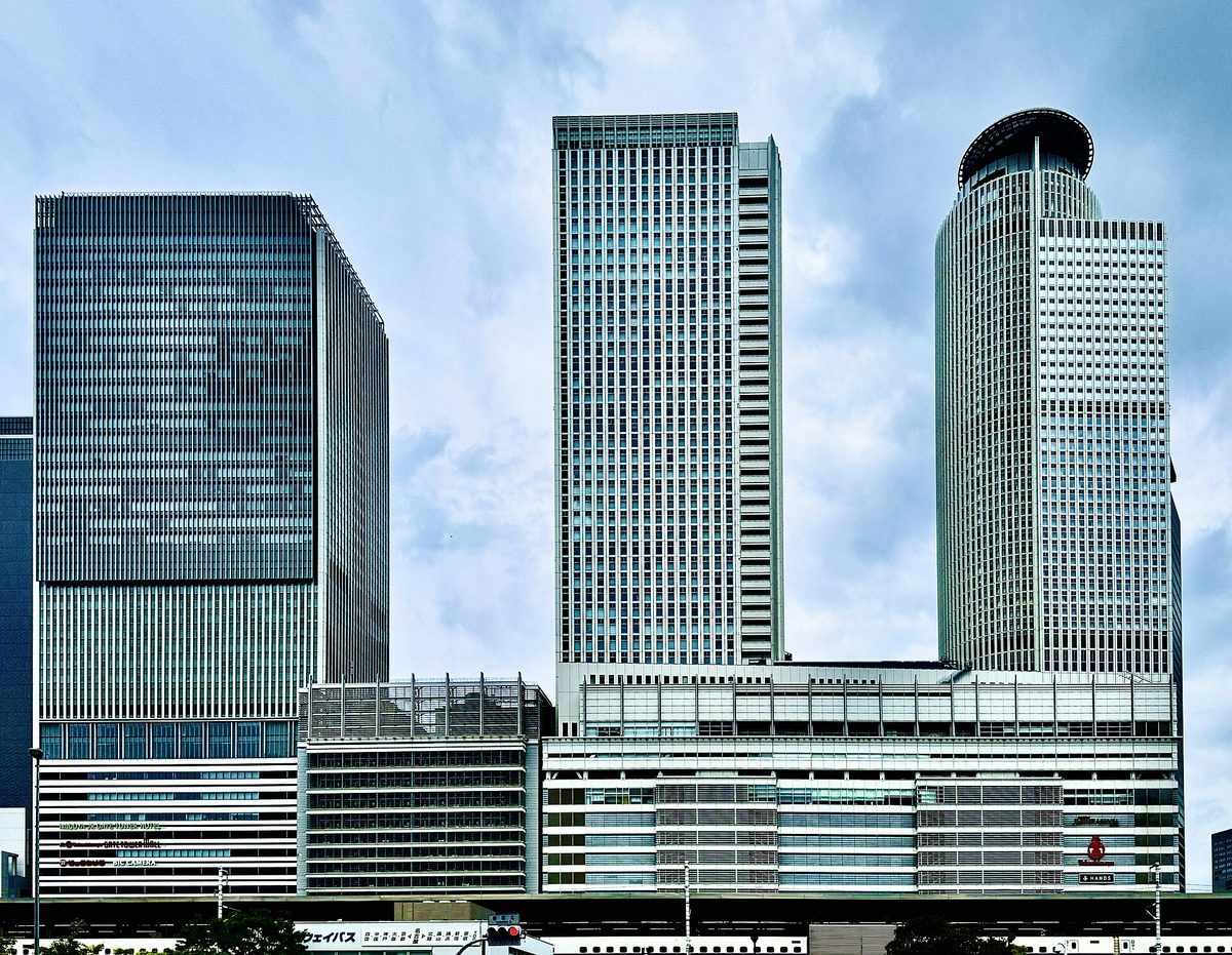 The twin round towers of JR Central Towers and the JR Gate Tower above Nagoya Station under a blue sky