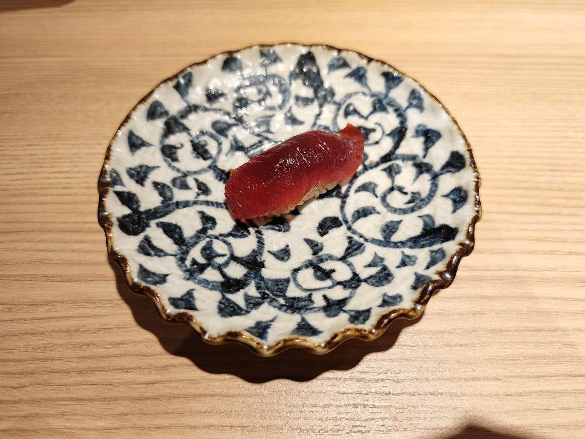 A piece of tuna nigiri on a blue and white patterned plate