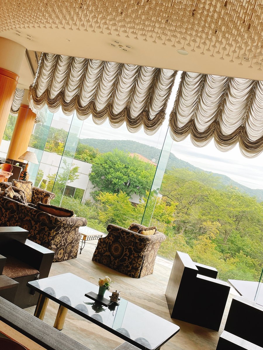 A lounge with armchairs and large windows looking out over green hills and the sea