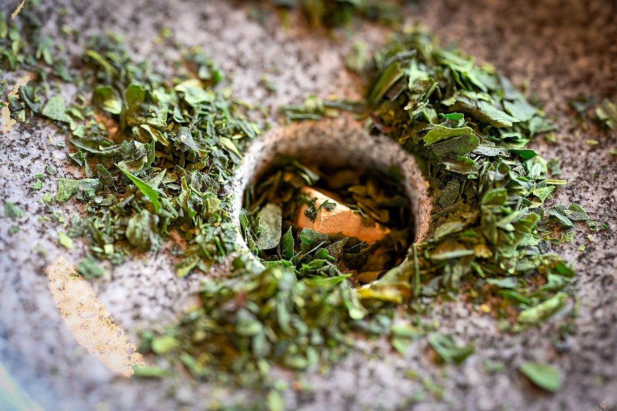 Close-up of dried tencha leaf pieces around the feed hole of a gray granite stone mill