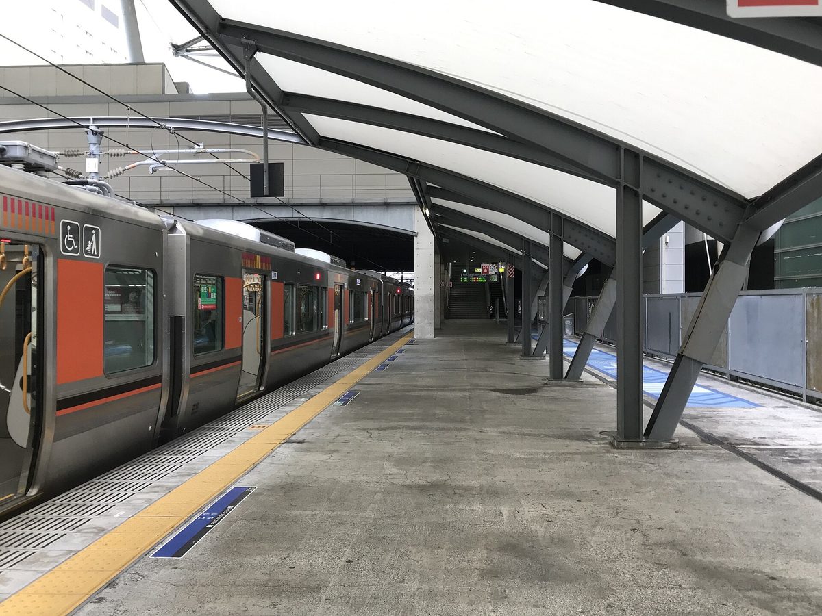 An orange and silver JR train waiting under the curved roof of Universal City Station