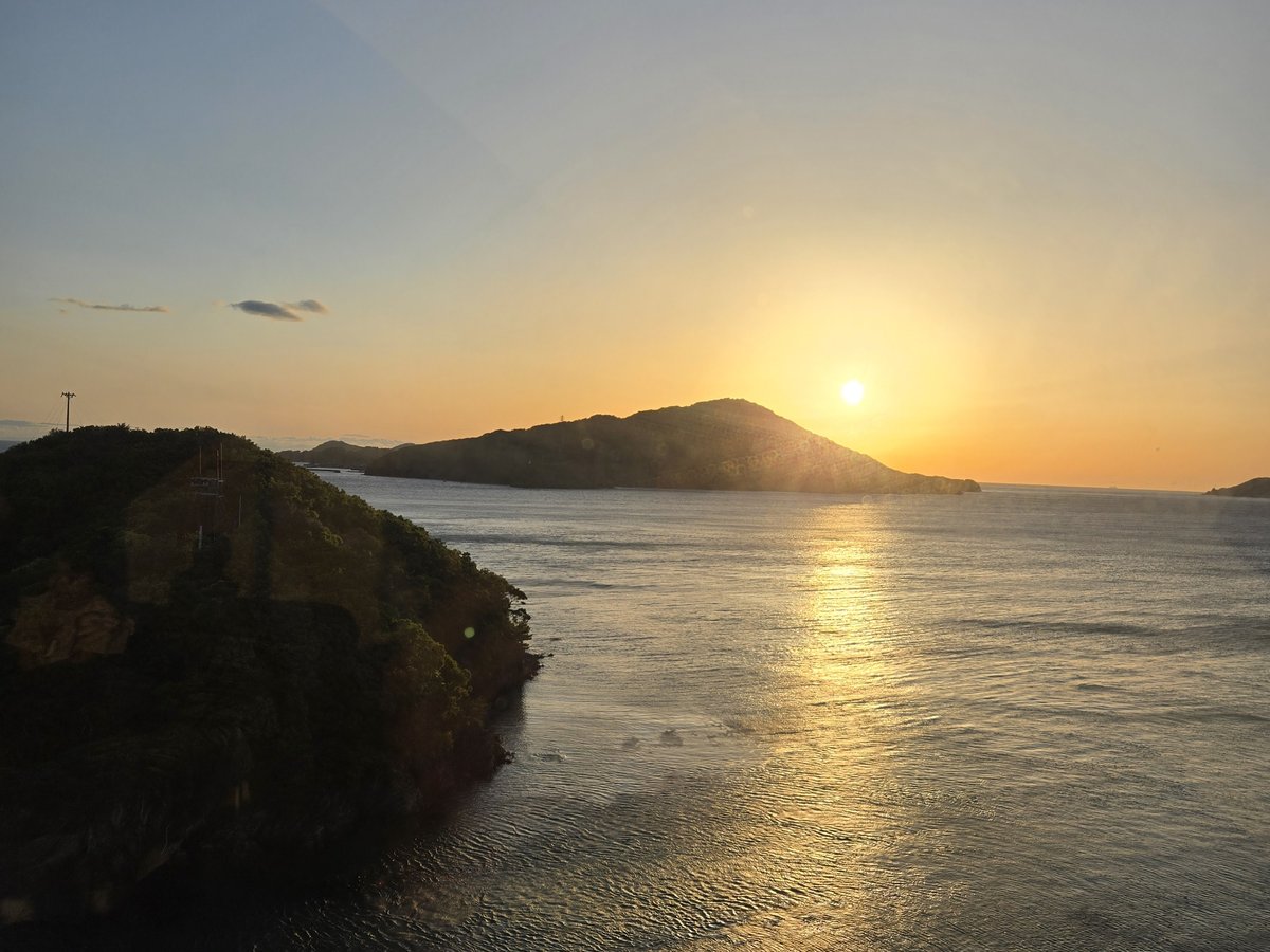 The sun setting behind an island over a calm bay, seen from a high window